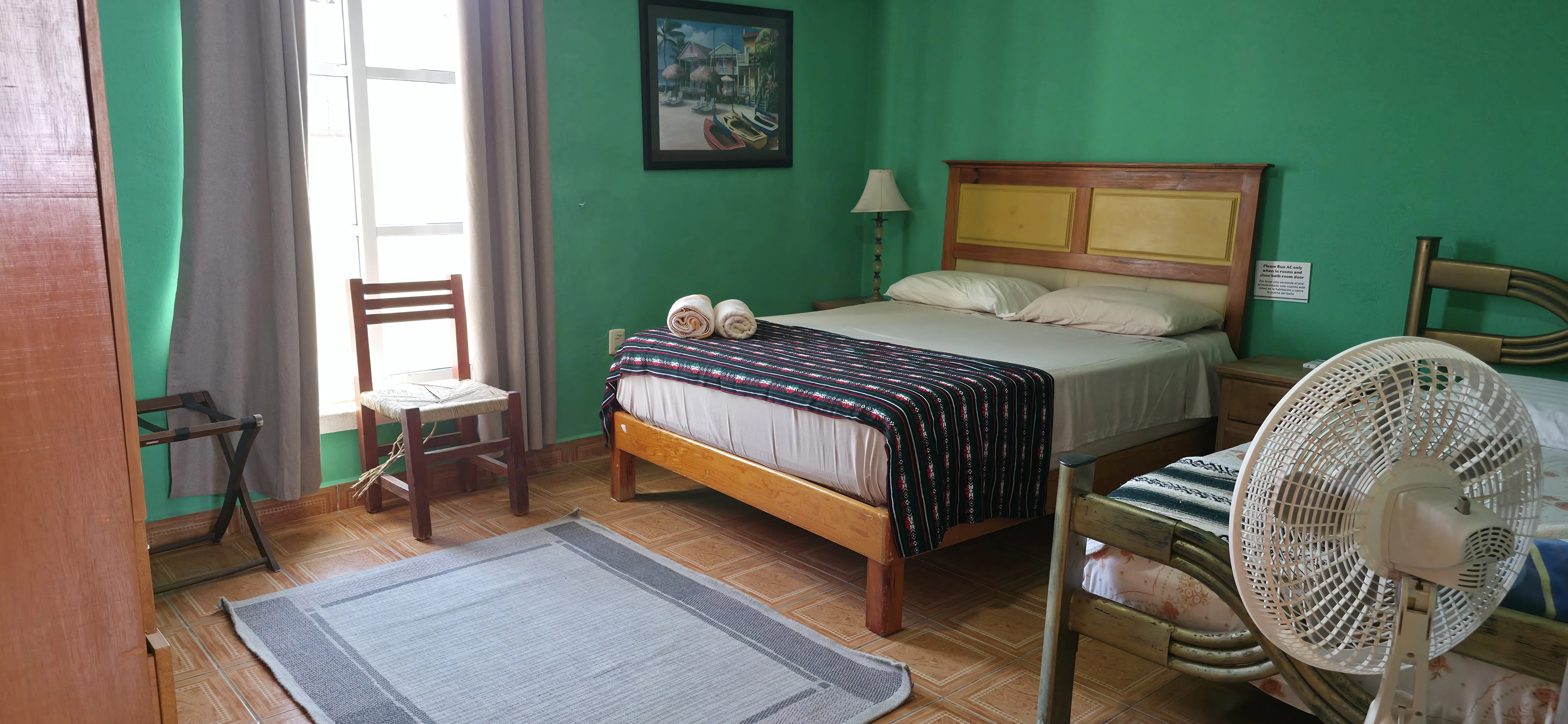 Recámara verde con cama queen y arte de playa