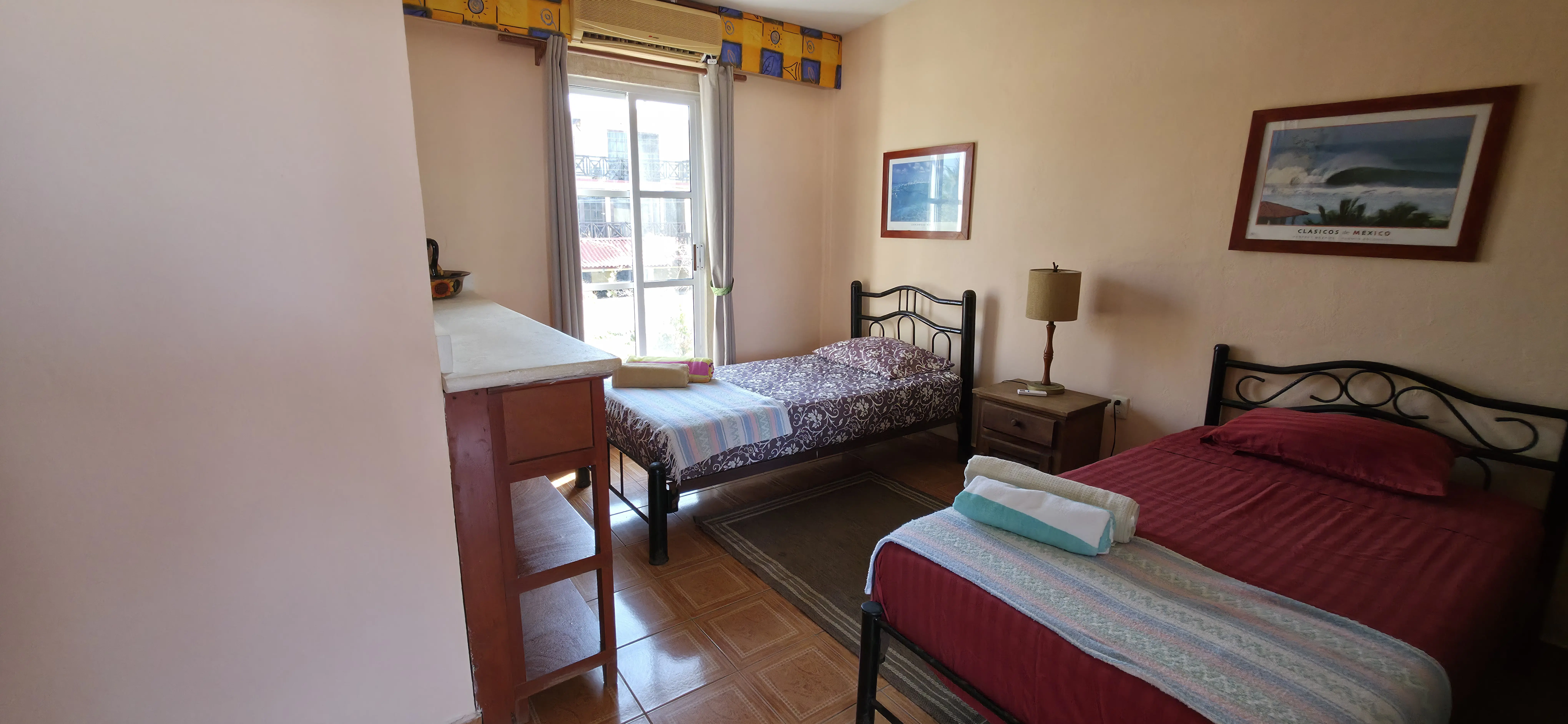 Recámara con camas individuales de herrería y vista al balcón