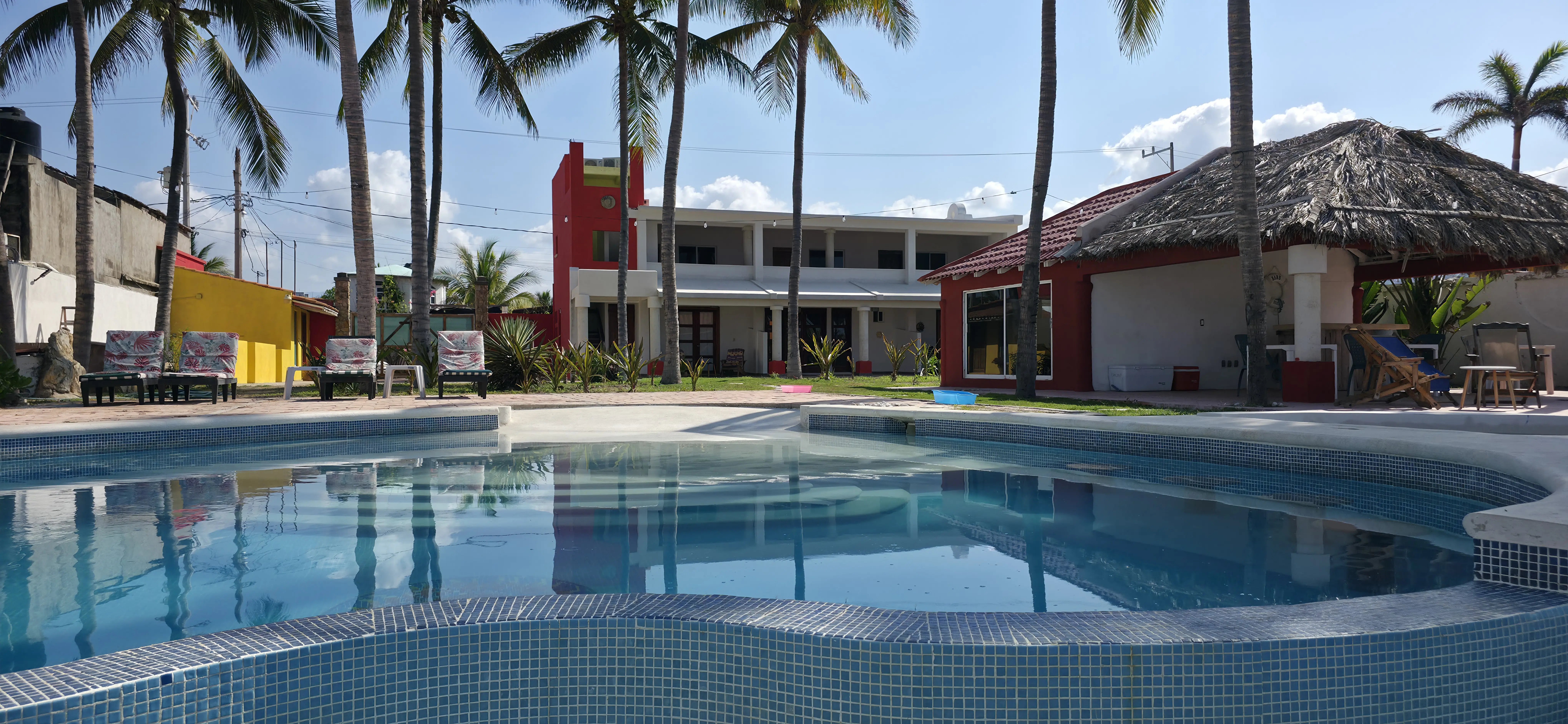 La alberca con la fachada de la casa de dos pisos al fondo