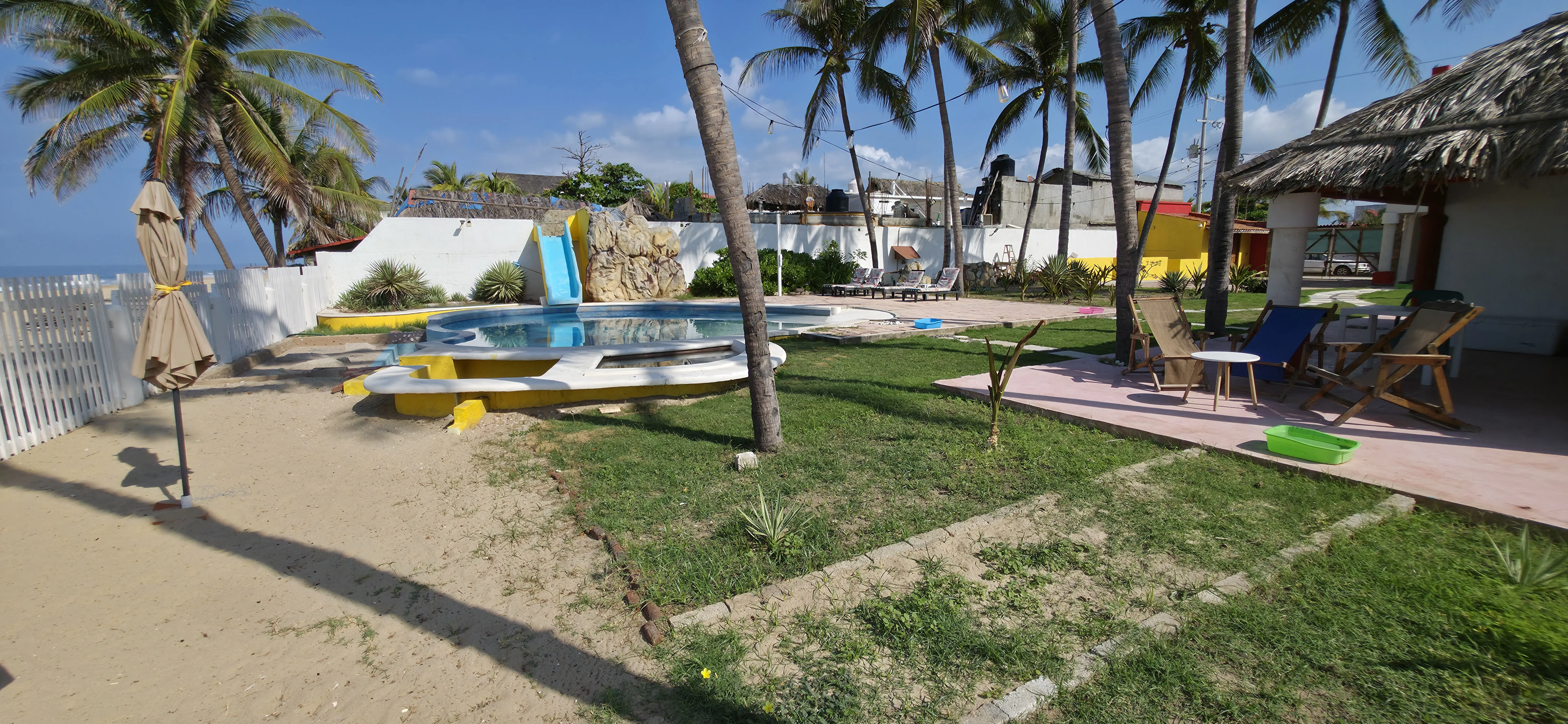 Alberca con tobogán y cerca blanca frente a la playa